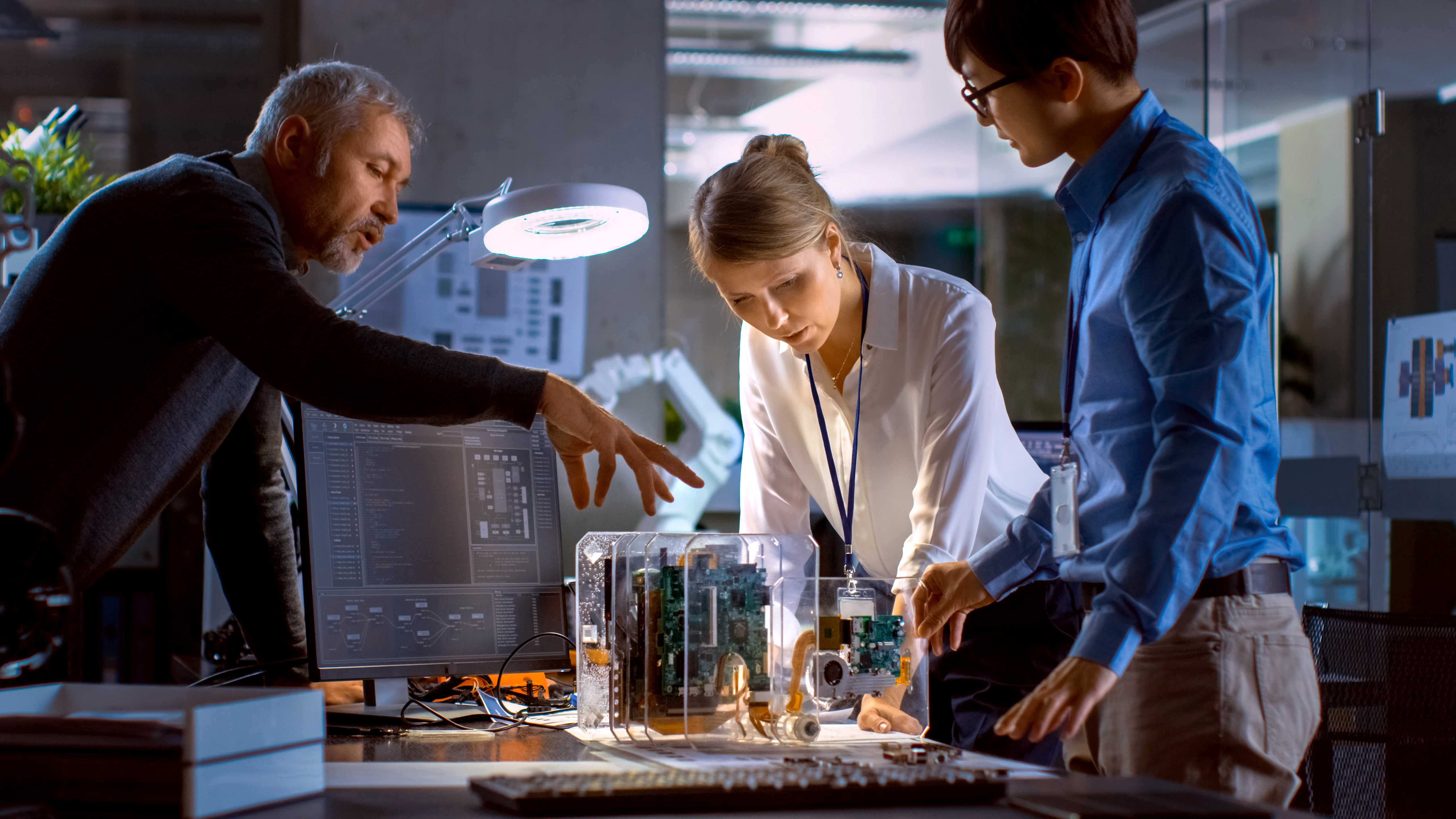 Three professionals standing around a complex mechanical device on a table.